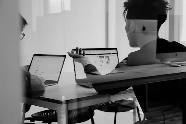 two professionals working on laptops